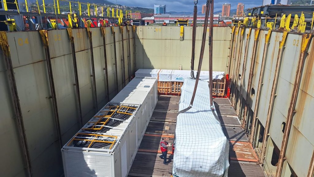 Large industrial trailers and cargo containers arranged inside the ship's hold.