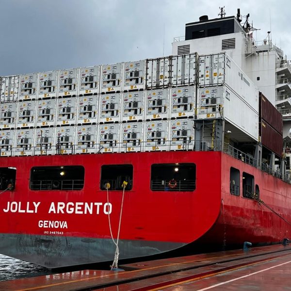 Rear view of the Jolly Argento docked at port, loaded with stacks of white reefer containers.