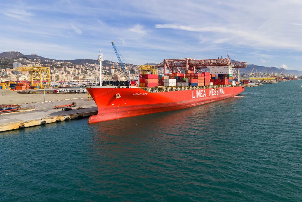 Side view of the Jolly Oro docked at the Messina terminal with port cranes in the background.