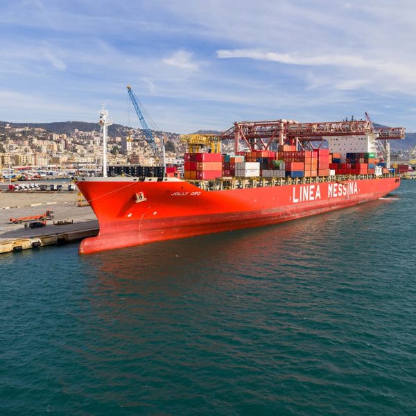 Side view of the Jolly Oro docked at the Messina terminal with port cranes in the background.