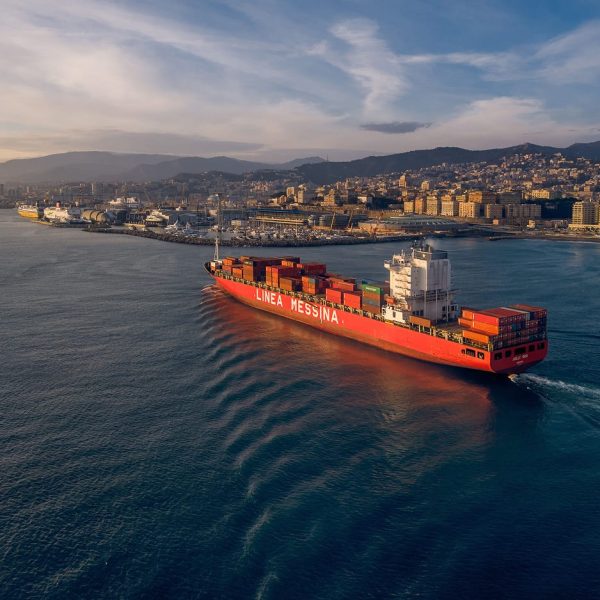 High-angle aerial shot of the Jolly Oro sailing near the coast during golden hour.