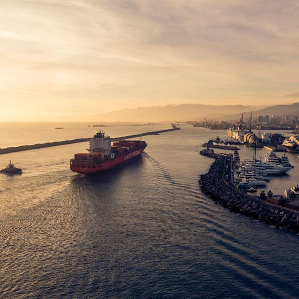 Aerial sunset view of the Jolly Oro container ship leaving the port accompanied by a tugboat.