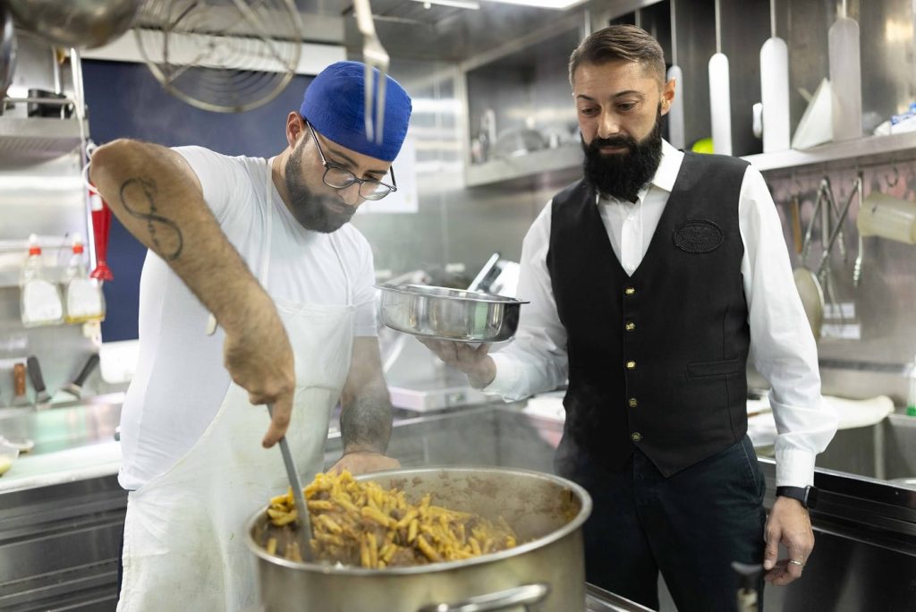 Cook and steward preparing food in the ship's galley.
