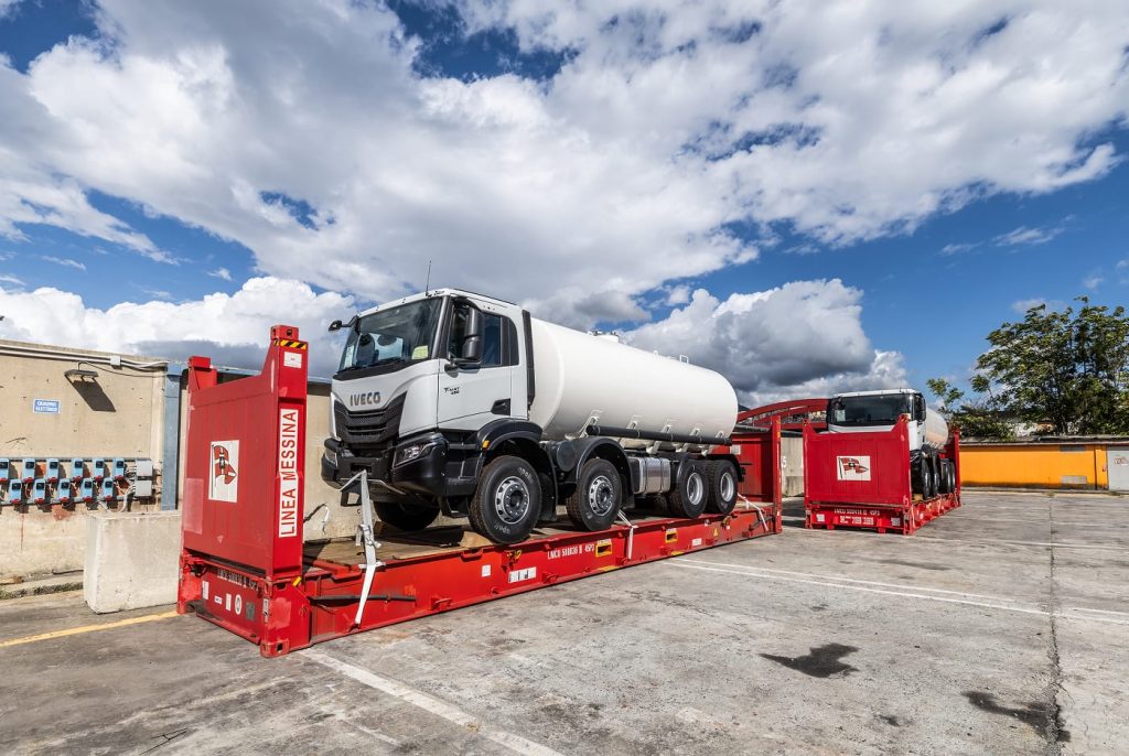 An Iveco T-Way tanker truck secured on a red flatrack container ready for shipping.