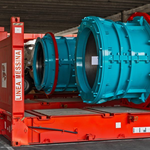 Large blue industrial cylinders secured on red Messina Line flatrack containers.