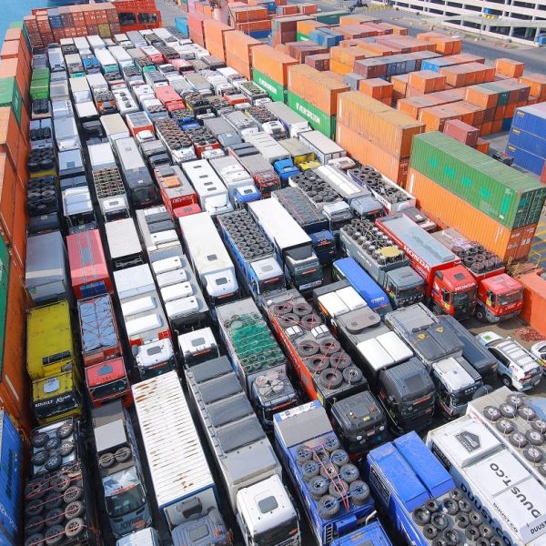 High-angle view of the deck packed with Dakar Rally trucks and colorful shipping containers.