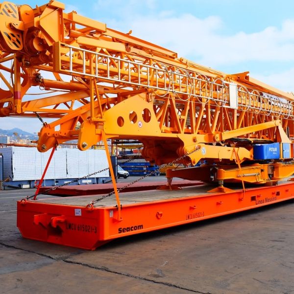 A massive yellow Potain crane component positioned on an orange Seacom roll-trailer.