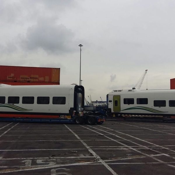 Two Talgo passenger cars positioned on trailers at the port terminal near Messina containers.