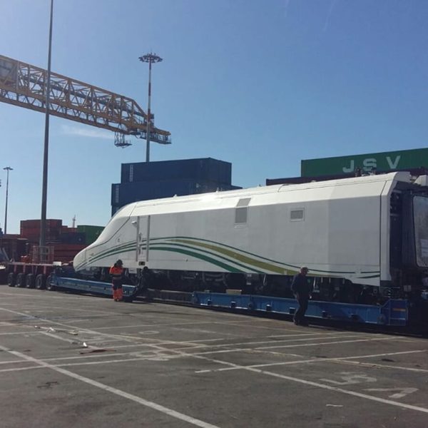 A Talgo power car being carefully aligned on a heavy-duty multi-axle trailer for loading.